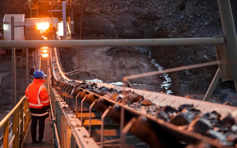 Nyngan Australia June 20th 2012 : Shallow depth of field image of a miner inspecting ore rocks on a conveyor in NSW Australia